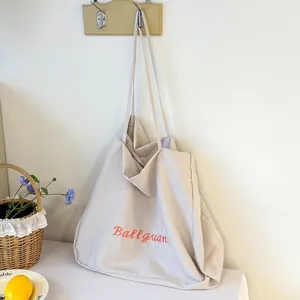 Detailed view of a large beige canvas tote bag with stylish pink Ballguan embroidery