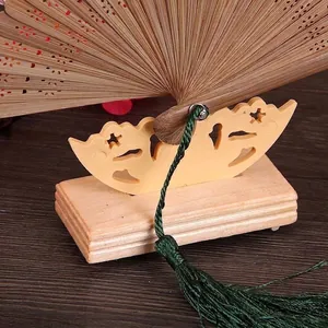Detalle de un soporte para abanico en madera natural con borla decorativa verde