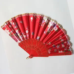Close-up of red floral satin folding fan featuring delicate gold lace trim and plastic ribs