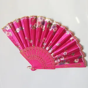 Close-up of a pink floral folding fan with gold lace trim and plastic ribs.