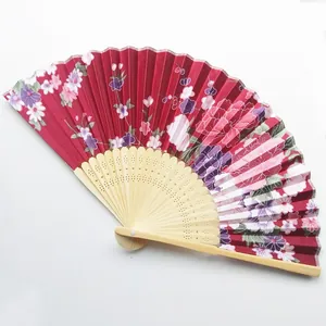 Detailed view of red floral satin fabric and natural bamboo ribs of a folding fan