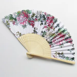 Detail view of a Japanese folding fan with floral satin fabric and carved wood frame.