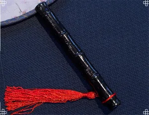 Close-up detail of a black bamboo-shaped handle and red tassel on a Chinese round fan