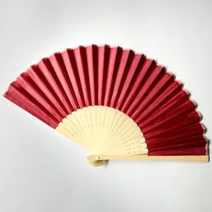 Detail view showing a deep red silk folding fan with intricate bamboo rib carvings.