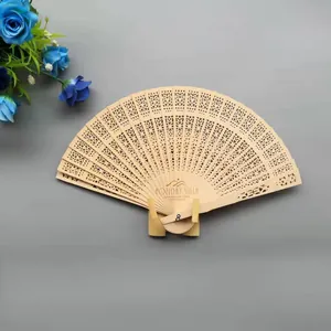 Vista detallada de un abanico plegable de madera con grabados calados y texto