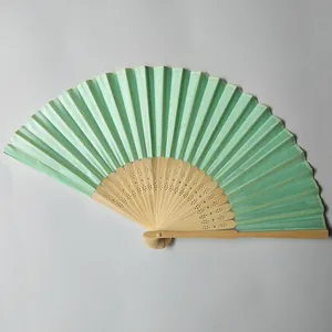 Detail shot of a light green silk folding fan with elegant carved bamboo frame