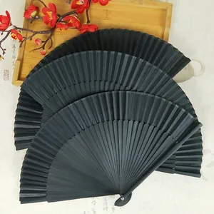 Detail view of three elegant black bamboo folding fans with ribs displayed on a wooden tray