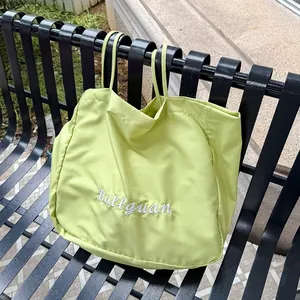 Light green Harajuku style tote bag with Ballguan embroidery hanging on a metal bench.