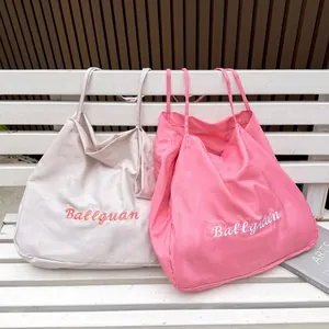 Casual canvas tote bags in pink and beige with Ballguan embroidery on a bench