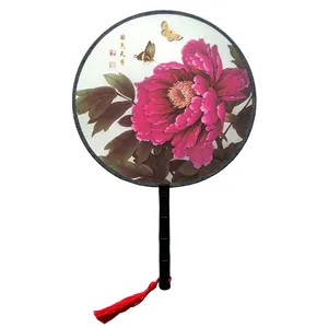 Detail view of a traditional Chinese round fan with pink peony and red tassel.