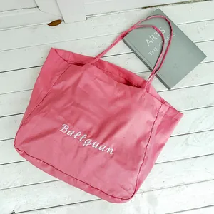 Pink minimalist large capacity tote bag shown flat on a white wooden surface with props
