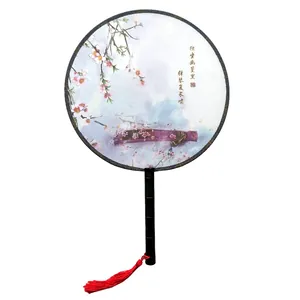 Detail of a traditional Chinese round fan with cherry blossom pattern and red tassel.