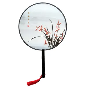 Detailed view of a vintage Chinese round fan with elegant orchid pattern and a red silk tassel