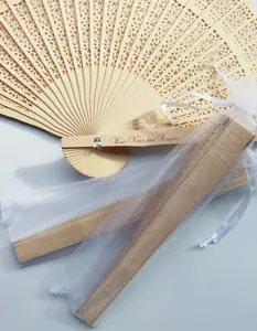 Detalle macro de abanicos de boda de madera grabados con bolsas de regalo de organza blanca