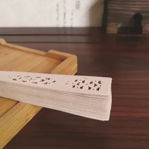 Primer plano detallado de los tallados florales en un abanico de madera para bodas