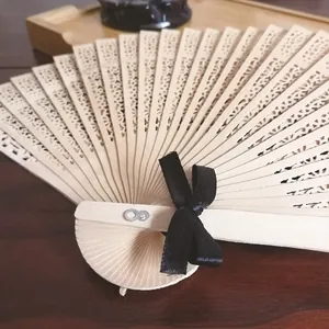 Detalle de un abanico de madera tallado con un lazo de cinta de raso negro elegante.