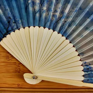 Close-up of elegant blue silk folding fan featuring Monet's Impression Sunrise artwork design