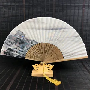 Vue détaillée d'un éventail chinois avec peinture de paysage et pompon jaune et support