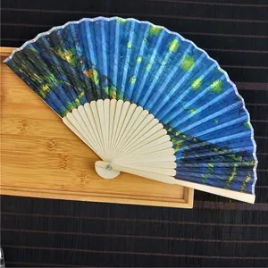 Close-up detail of a traditional bamboo folding fan featuring The Starry Night painting