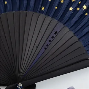 Close-up of a starry sky folding fan with gold stars and black bamboo ribs.
