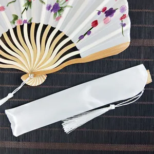 Elegant floral satin folding fan with white storage sleeve and decorative tassels.
