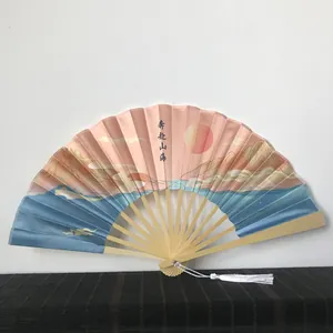 Detailed view of traditional Chinese folding fan with landscape pattern and white tassel.