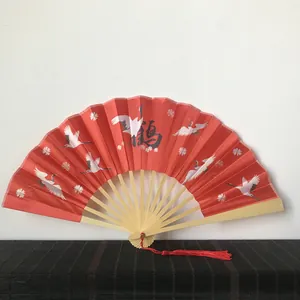 Traditional red folding fan with elegant crane pattern and bamboo frame decoration