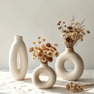Three minimalist white ceramic donut vases featuring elegant dried flower arrangements