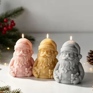 Detail von drei brennenden Weihnachtsmann-Kerzen in Rosa, Gelb und Grau für Weihnachten