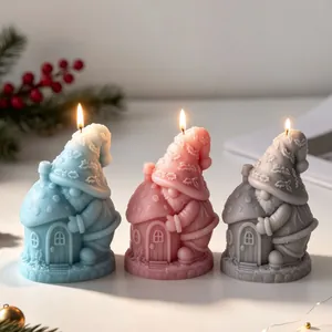 Three gnome mushroom house candles in blue pink and grey lit for holiday home decoration.