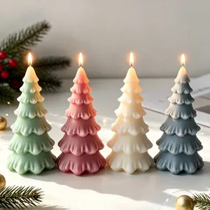 Detail view of four lit Christmas tree candles in pastel colors with festive decor