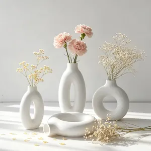 Minimalist white matte donut vases with hollow oval designs and floral arrangements