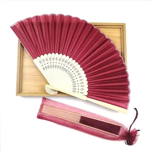 Detail of a burgundy folding fan with bamboo ribs and a matching organza gift bag