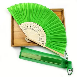 Green bamboo folding fan displayed with a matching organza gift bag on a wooden tray