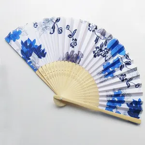 Primer plano de abanico plegable tradicional con flores azules y bambú tallado
