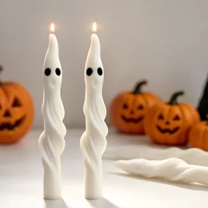 Pair of lit ghost-shaped spiral candles standing against a festive Halloween background