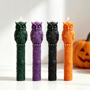 Detailweergave van vier brandende Halloween uil stompkaarsen in verschillende kleuren.