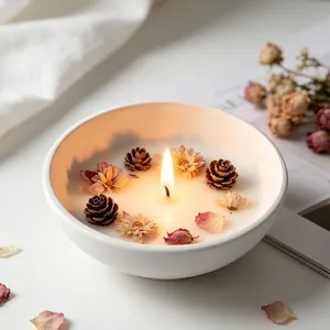 Close-up of a DIY aromatherapy candle bowl featuring dried flowers and pine cones
