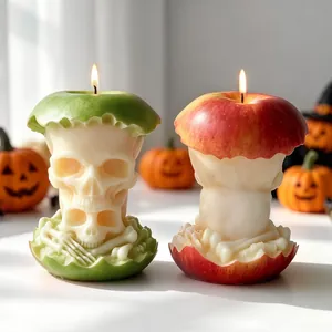 Détail macro de deux bougies d'Halloween en forme de crâne dans des pommes rouges et vertes