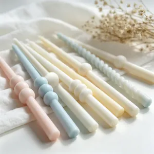 Close-up of pastel spiral and beaded aromatherapy candles on white linen background.