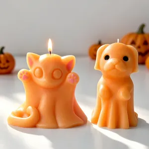 Primo piano di adorabili candele di cera a forma di gatto e cane fantasma arancio.