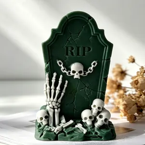 Detailed macro view of a dark green Halloween tombstone candle with skull decorations.