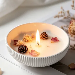 Close-up of a handmade scented candle bowl with dried flower and pinecone decorations