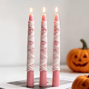 Detail view of pink mummy Halloween candles with realistic ribbon texture and lit flames