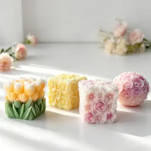 Detailed view of four assorted floral relief scented candles in soft pastel colors.