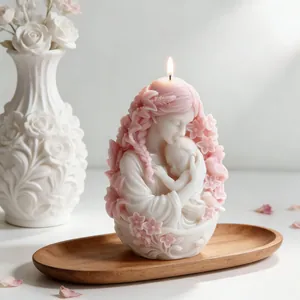 Detailed view of a lit mother and baby sculpted candle with pink floral accents on a wooden tray