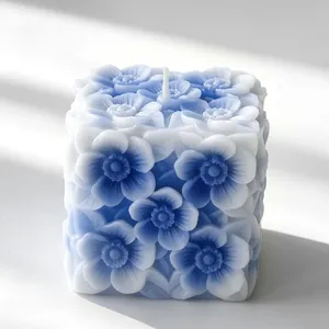 Dettaglio di una candela profumata a cubo con rilievo floreale blu e bianco elegante