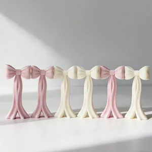 Vue rapprochée de bougies artisanales en forme de nœud, rose et crème, fini mat