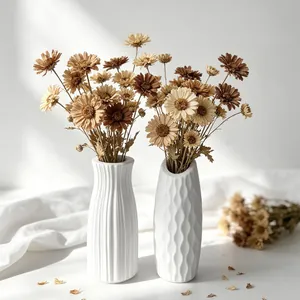 Detailed view of two white minimalist vases with vertical and honeycomb textures.