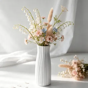 Elegant white ribbed ceramic vase with a bouquet of spring flowers on a sunlit table